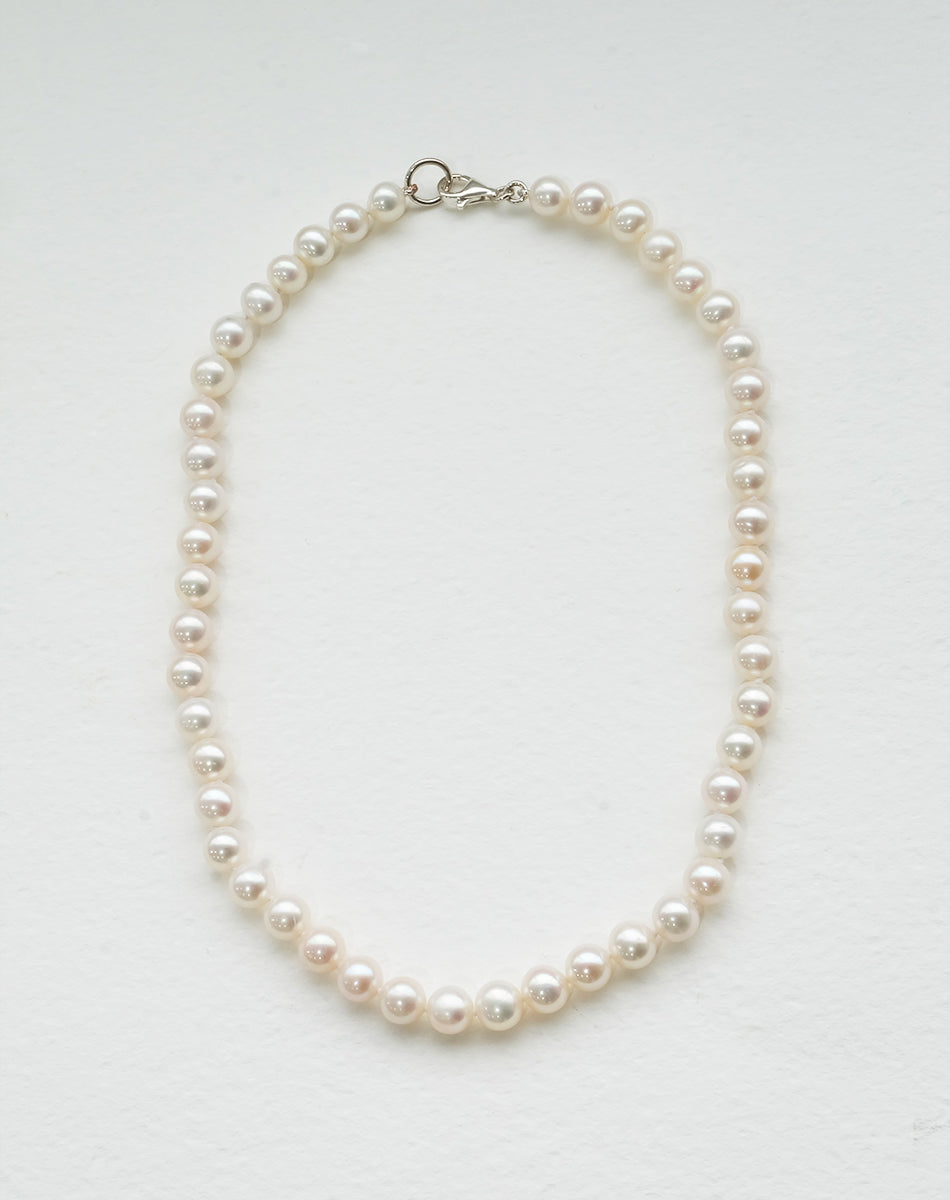 A freshwater pearl necklace with a classic round pearl design, strung on a silk thread and knotted.