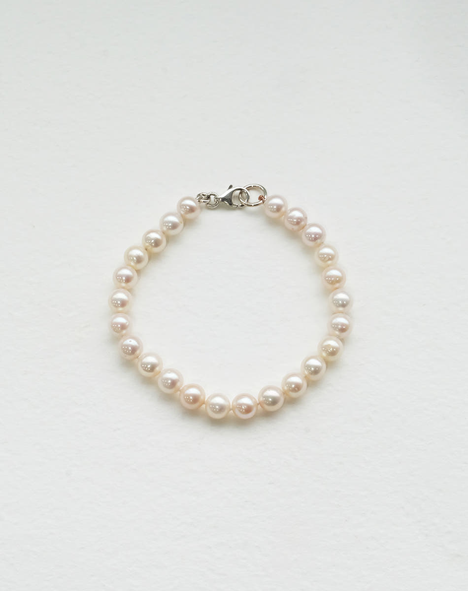 A sterling silver pearl anklet featuring a series of round pearls strung on a silk thread with a classical knotting 
