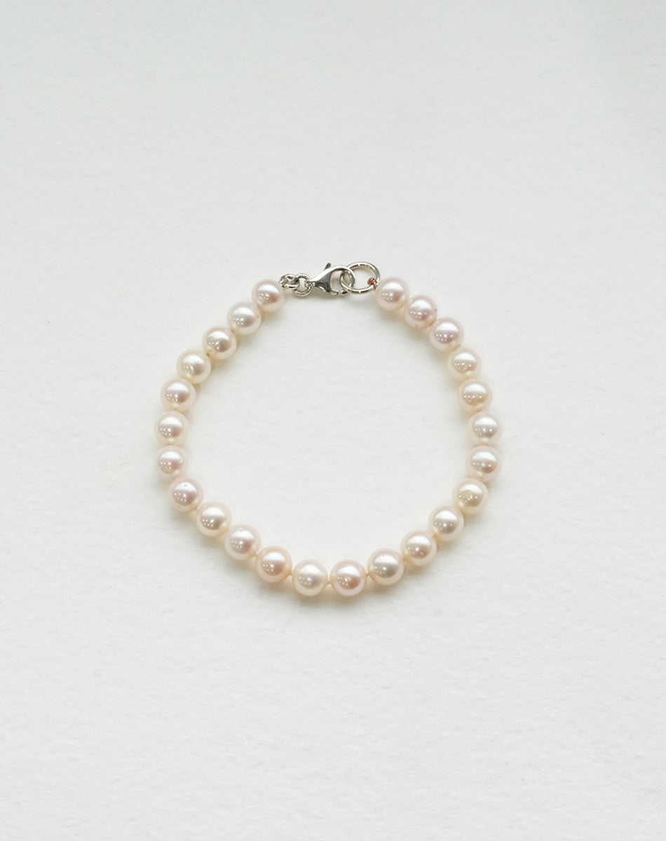 A sterling silver pearl anklet featuring a series of round pearls strung on a silk thread with a classical knotting 