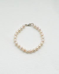 A sterling silver pearl anklet featuring a series of round pearls strung on a silk thread with a classical knotting 