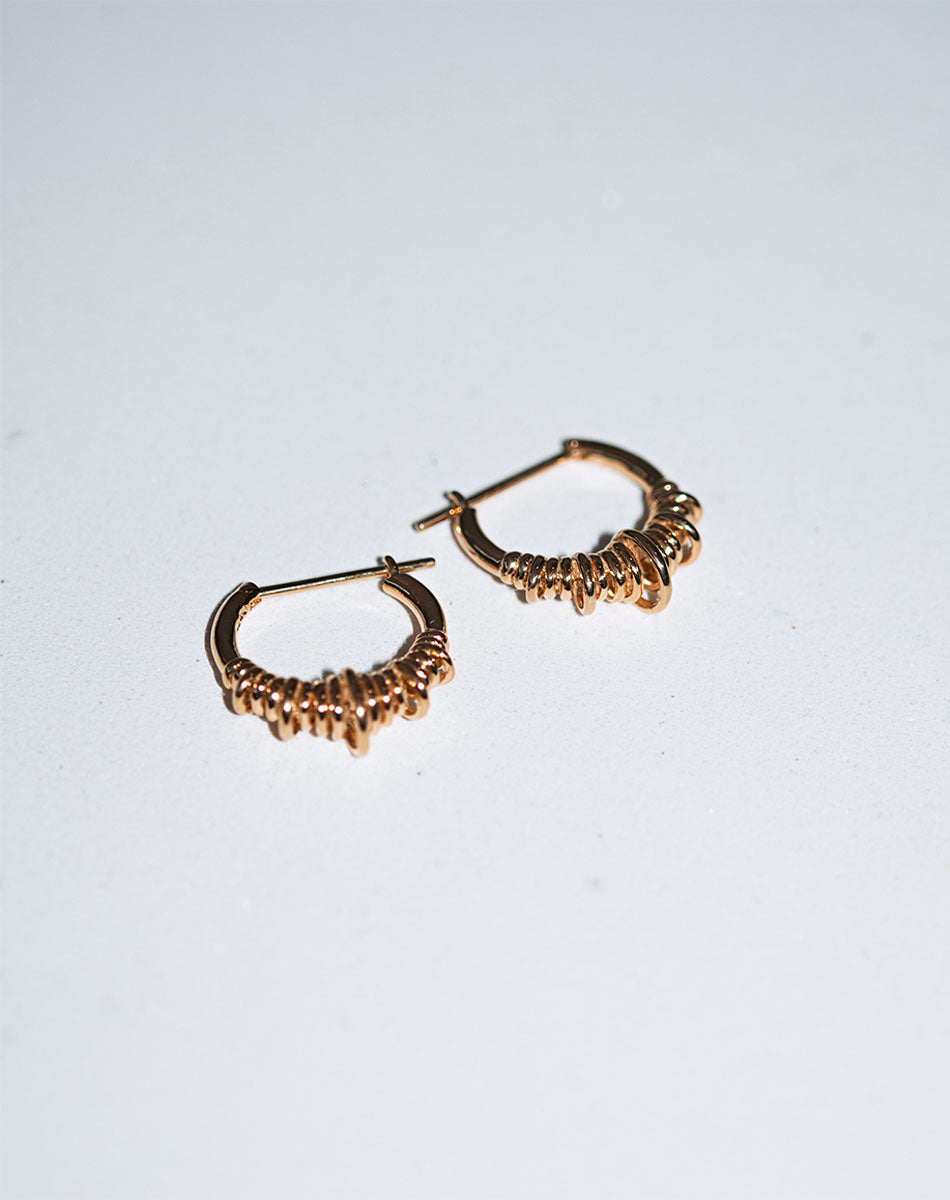 A pair of small hoop earrings made of sterling silver, with a series of rings suspended on a hoop.