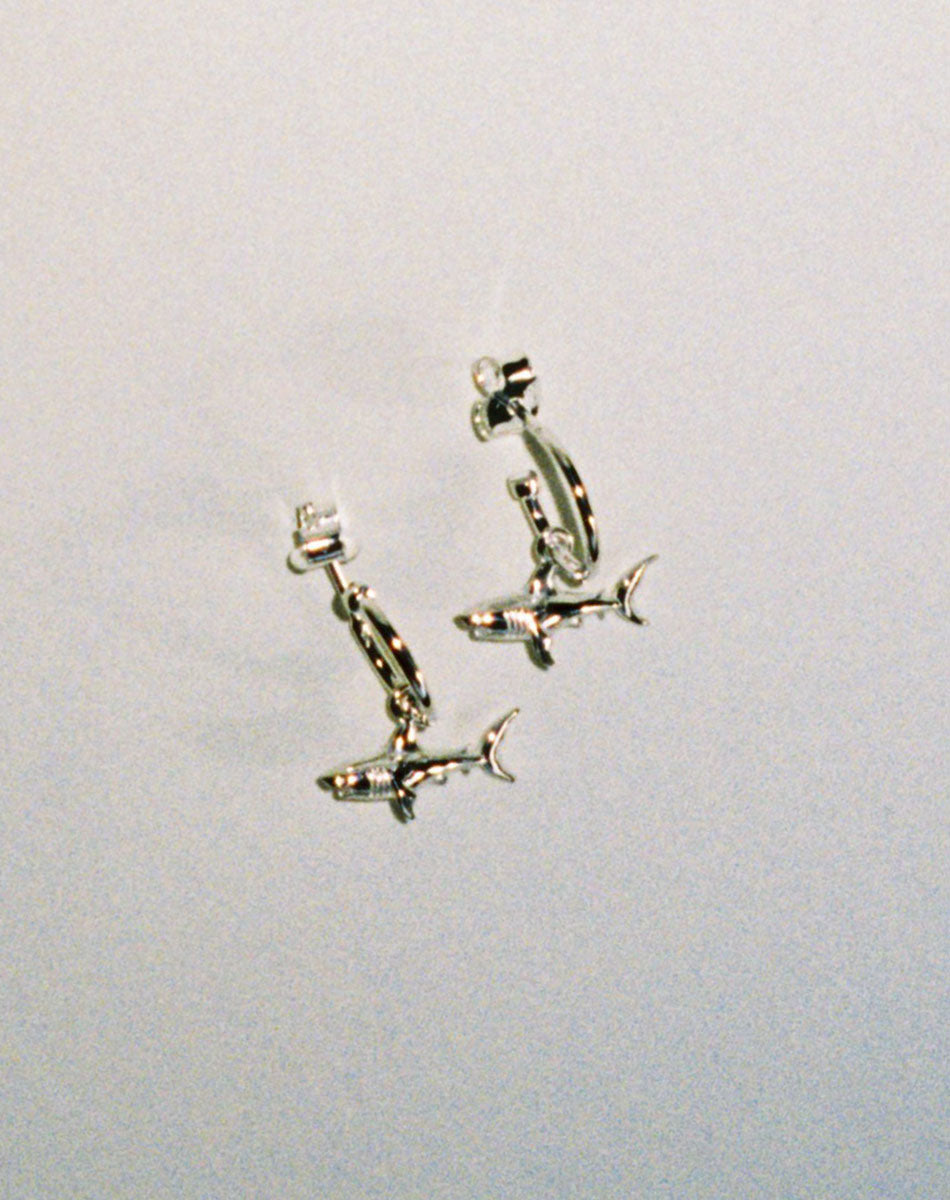 Sterling silver hoop earrings with shark charms attached.
