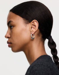 Silver hoop earrings with dotty details, worn by a model