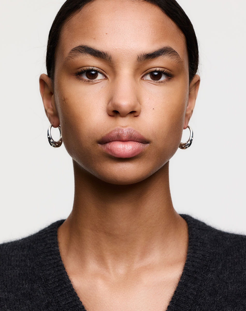 Silver hoop earrings with dotty details, worn by a model