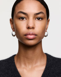 Silver hoop earrings with dotty details, worn by a model