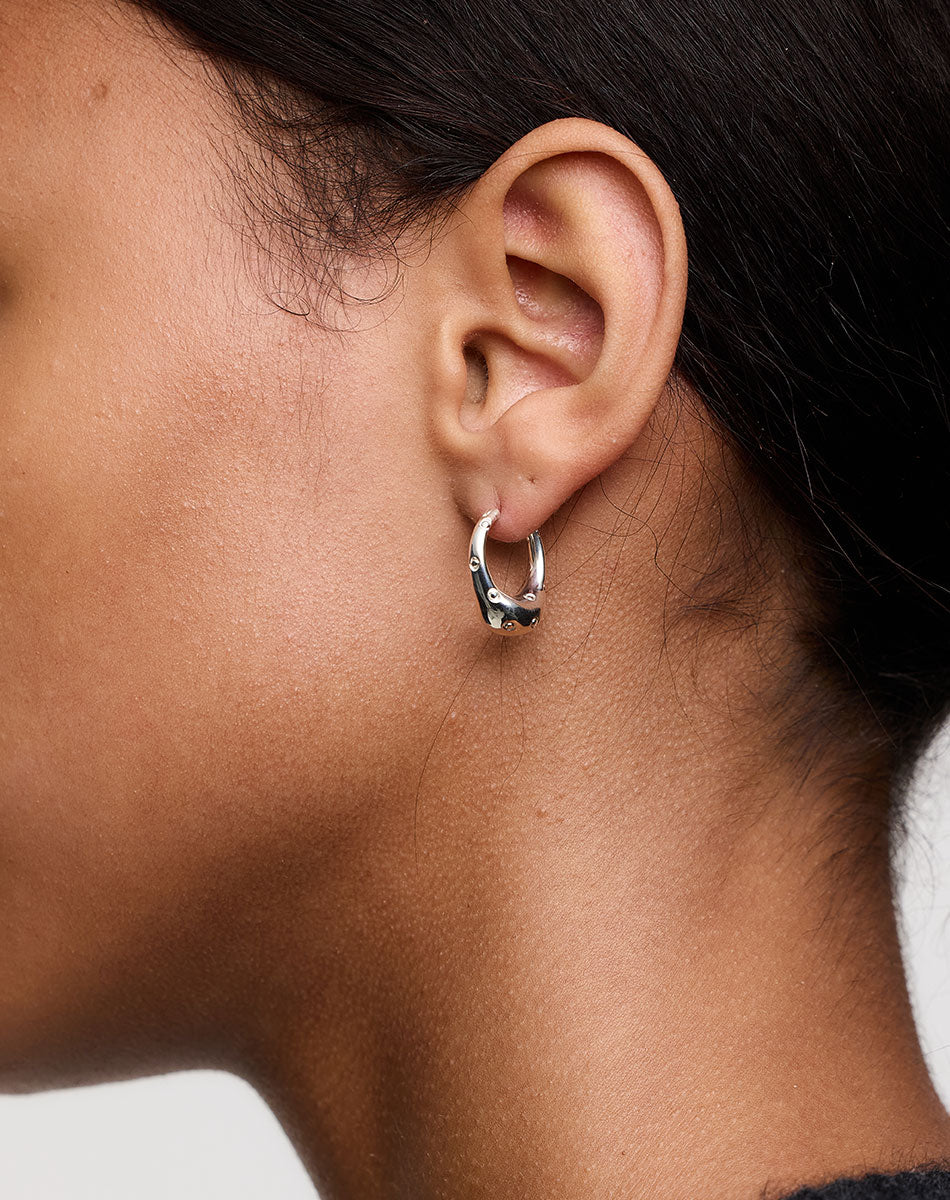 Silver hoop earrings with dotty details, on an ear