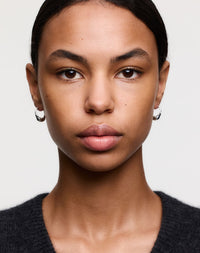 Silver hoop earrings with dotty details, on a model