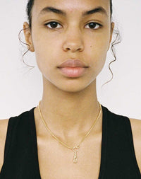 A gold swivel necklace with a  for attaching your favourite charms worn on model