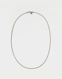 A sterling silver wheat chain necklace laid out on a plain surface.