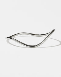 A sterling silver bracelet with a minimalist design that transitions into a curvy, rounded band.