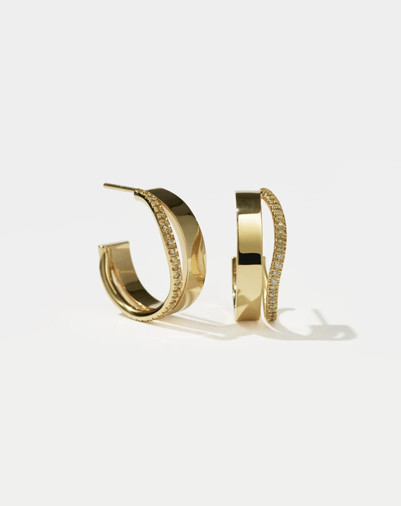 A pair of gold hoop earrings with a pave of diamonds set on the hoops.
