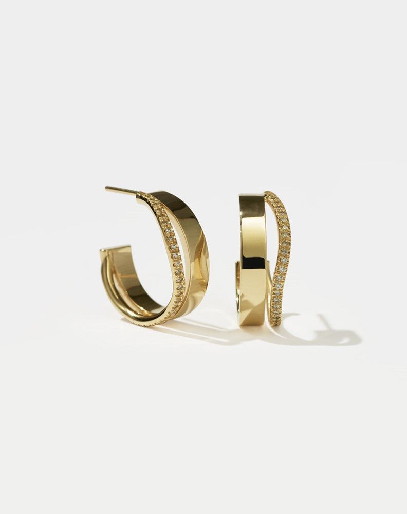 A pair of gold hoop earrings with a pave of diamonds set on the hoops.