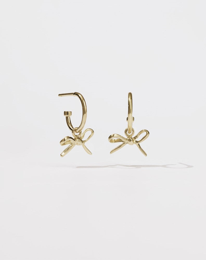 Gold hoop earrings with a small bow charms