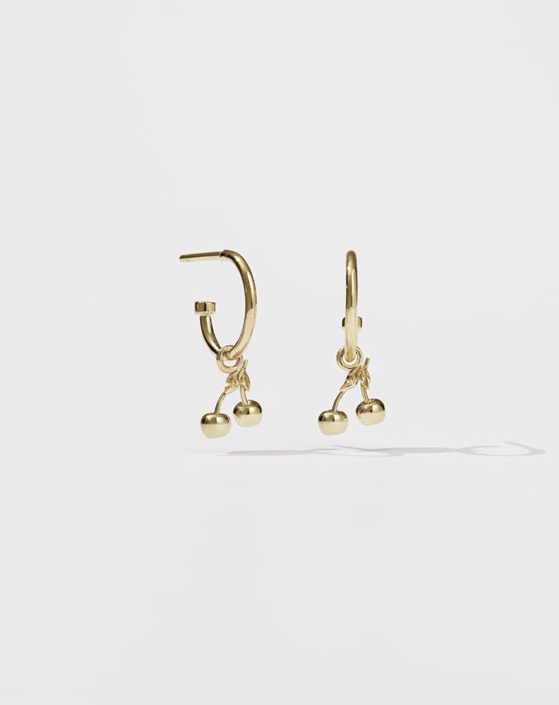 A pair of gold-plated hoop earrings with cherry charms attached