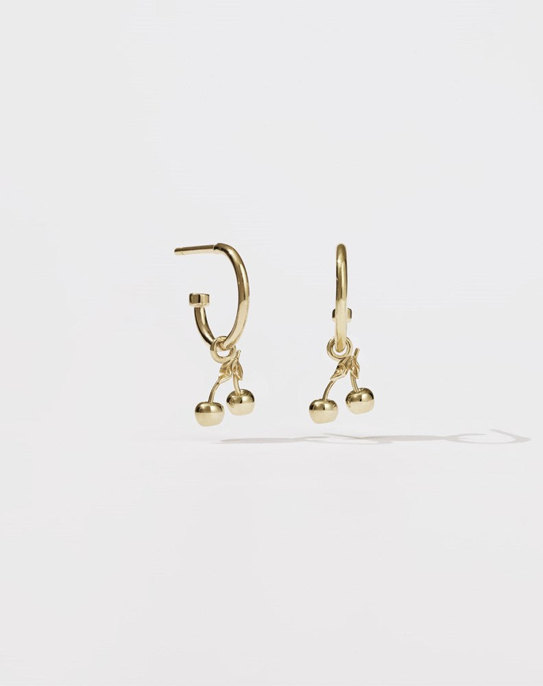 A pair of gold-plated hoop earrings with cherry charms attached