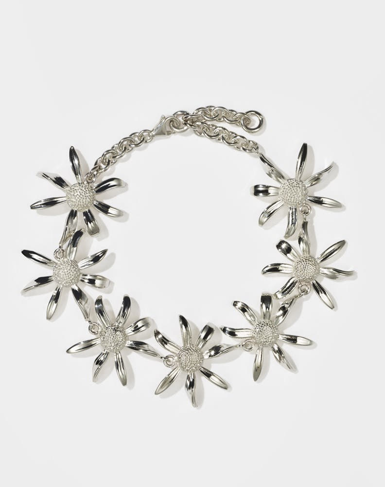 A sterling silver bracelet featuring a chain link design with seven daisy flower motifs