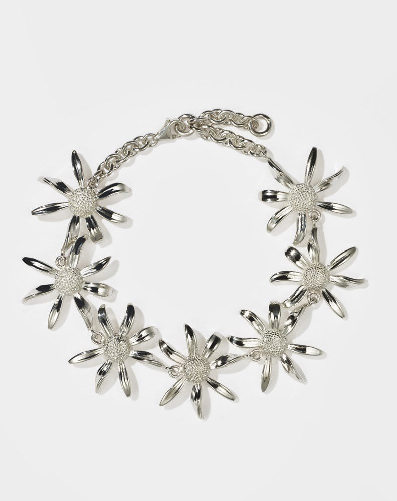 A sterling silver bracelet featuring a chain link design with seven daisy flower motifs
