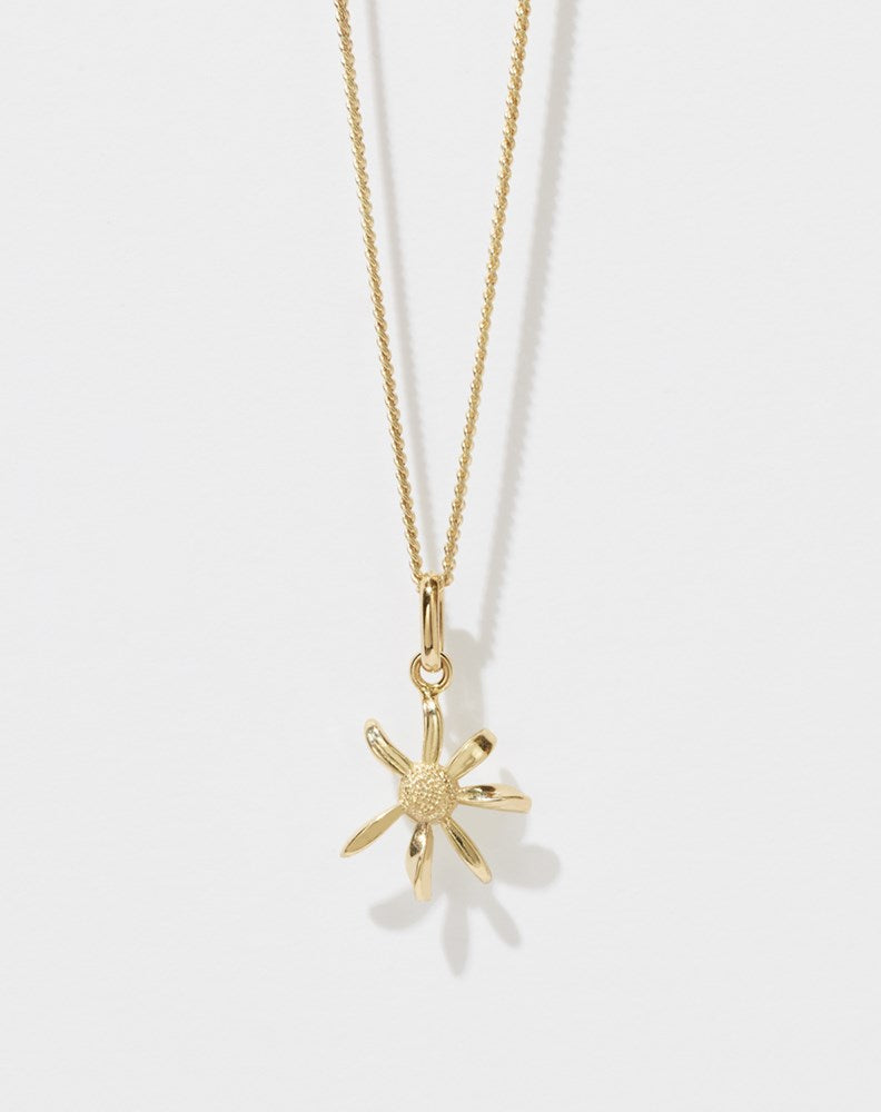 A gold daisy charm necklace on a fine chain