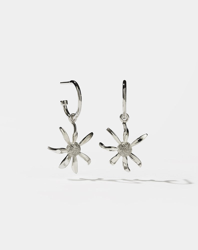 A pair of sterling silver hoop earrings with daisy charms attached