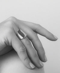 An oversized sterling silver signet ring with a flat rectangular platform for engraving, shown on a hand