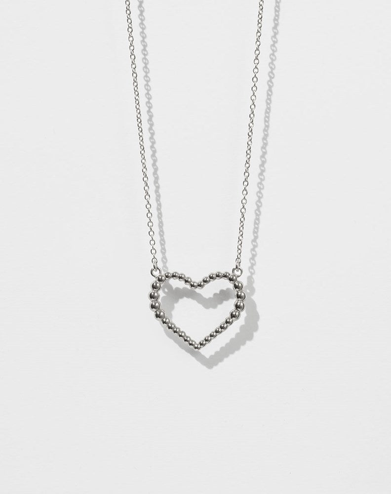 A sterling silver necklace with a heart-shaped pendant featuring a design of tiny bubbles.
