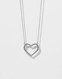 A sterling silver necklace with a heart-shaped pendant featuring a design of tiny bubbles.