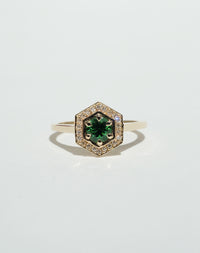 Meadowlark Jewellery’s Limited Edition Hex Engagement Ring 0.5ct in 9ct Yellow Gold, claw set with a round brilliant cut Tsavorite emerald Garnet centre stone, surrounded by a hexagon halo of pave set white diamonds. One of our most iconic and modern Ceremonial designs, made to order in New Zealand. Pair with our bestseller, the Diamond Eternity Band.