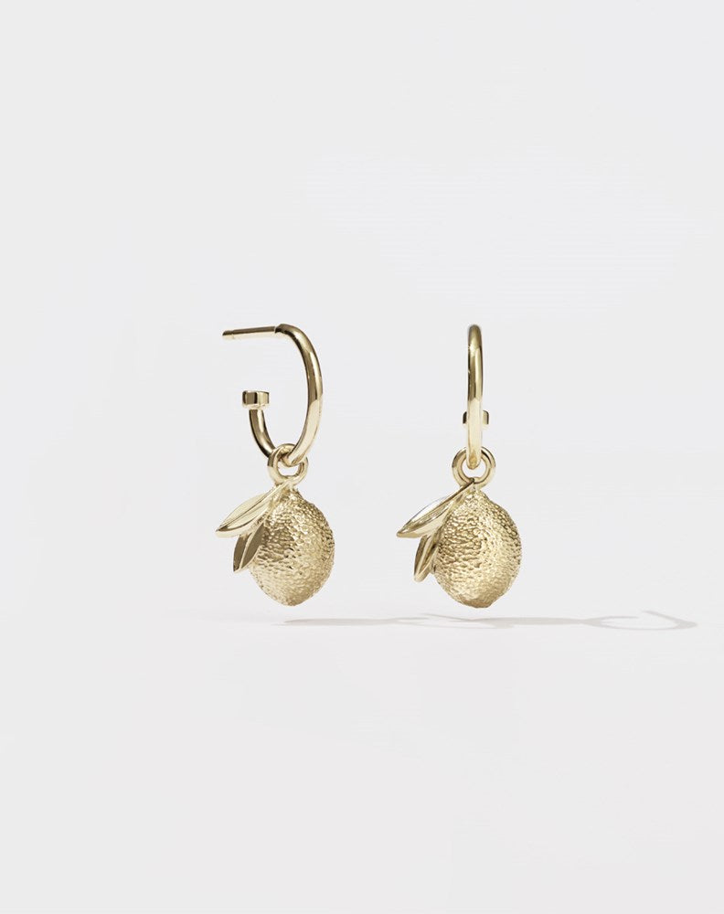 A pair of gold hoop earrings with lemon charm pendants attached