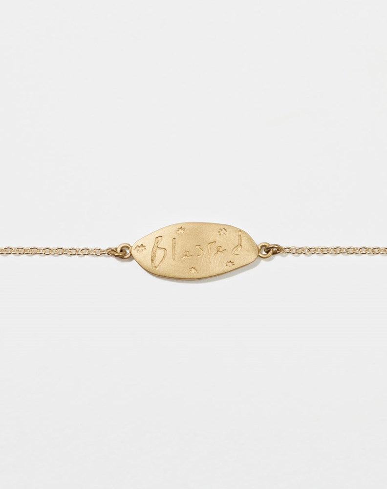 Meadowlark Jewellery’s Blessed Bracelet in 9ct Yellow Gold. A meaningful talisman for life’s journey, to serve as a daily reminder to honour the present and embrace gratitude for the quiet abundance all around us. A classic name tag in a matte, brushed texture inspired by ancient heirlooms hung from a fine diamond curb chain.  From the Dreams collection.