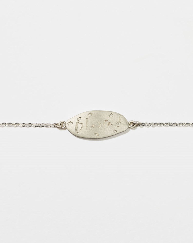 Meadowlark Jewellery’s Blessed Bracelet in Sterling Silver. A meaningful talisman for life’s journey, to serve as a daily reminder to honour the present and embrace gratitude for the quiet abundance all around us. A classic name tag in a matte, brushed texture inspired by ancient heirlooms hung from a fine diamond curb chain. From the Dreams collection.