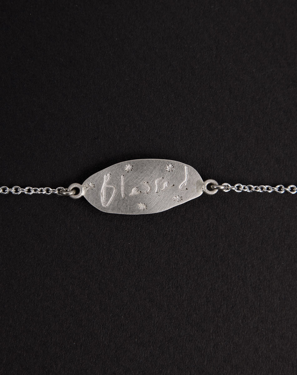 Meadowlark Jewellery’s Blessed Bracelet in Sterling Silver. A meaningful talisman for life’s journey, to serve as a daily reminder to honour the present and embrace gratitude for the quiet abundance all around us. A classic name tag in a matte, brushed texture inspired by ancient heirlooms hung from a fine diamond curb chain. From the Dreams collection.