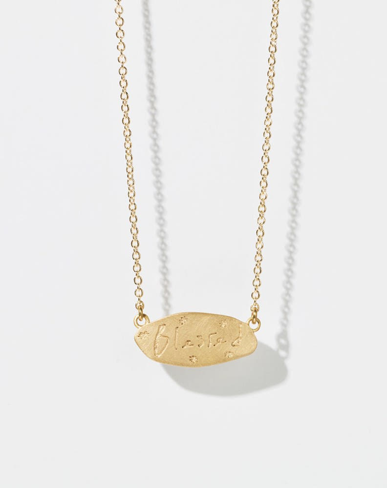 Meadowlark Jewellery’s Blessed Necklace in 9ct Yellow Gold. A meaningful talisman for life’s journey, to serve as a daily reminder to honour the present and embrace gratitude for the quiet abundance all around us. A classic name tag in a matte, brushed texture inspired by ancient heirlooms hung from a fine diamond curb chain. From the Dreams collection.