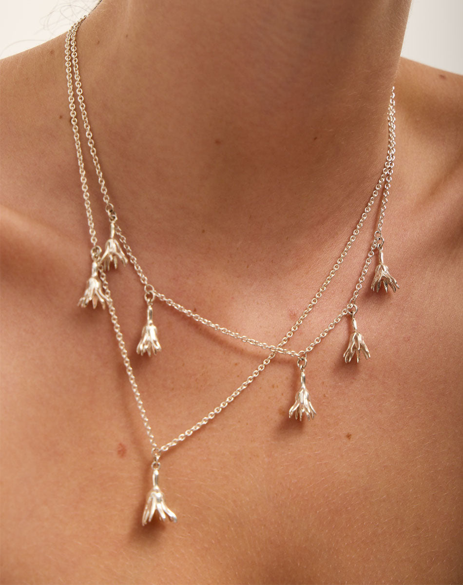 Meadowlark Jewellery’s Magda Two & Five Charm Necklaces in Sterling Silver. Two delicate, bell-shaped flower charms suspended from a fine diamond curb chain. A minimalist ode to blooming and the enduring cycles of life. From the Dreams collection.