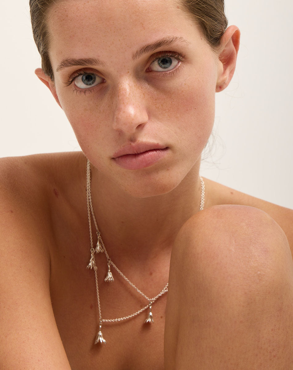 Meadowlark Jewellery’s Magda Five Charm Necklace in Sterling Silver. Five delicate, bell-shaped flower charms suspended from a fine diamond curb chain. A poetic celebration of growth, transformation, and the eternal rhythm of nature. A statement of quiet strength and beauty. From the Dreams collection.