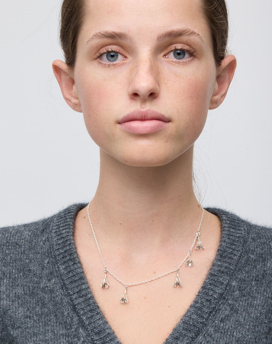 Meadowlark Jewellery’s Magda Five Charm Necklace in Sterling Silver. Five delicate, bell-shaped flower charms suspended from a fine diamond curb chain. A poetic celebration of growth, transformation, and the eternal rhythm of nature. A statement of quiet strength and beauty. From the Dreams collection.