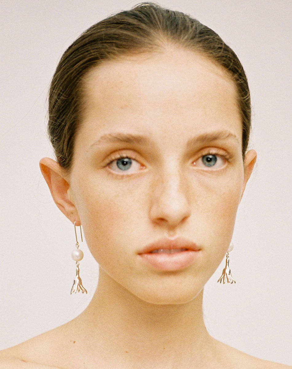 Meadowlark Jewellery’s refined Magda Pearl Earrings in Sterling Silver. An ethereal, bell-shaped flower charm suspended from a lustrous round, freshwater pearl – bringing an air of quiet luxury to any ensemble. Light-catching and dreamlike. From the Dreams collection.