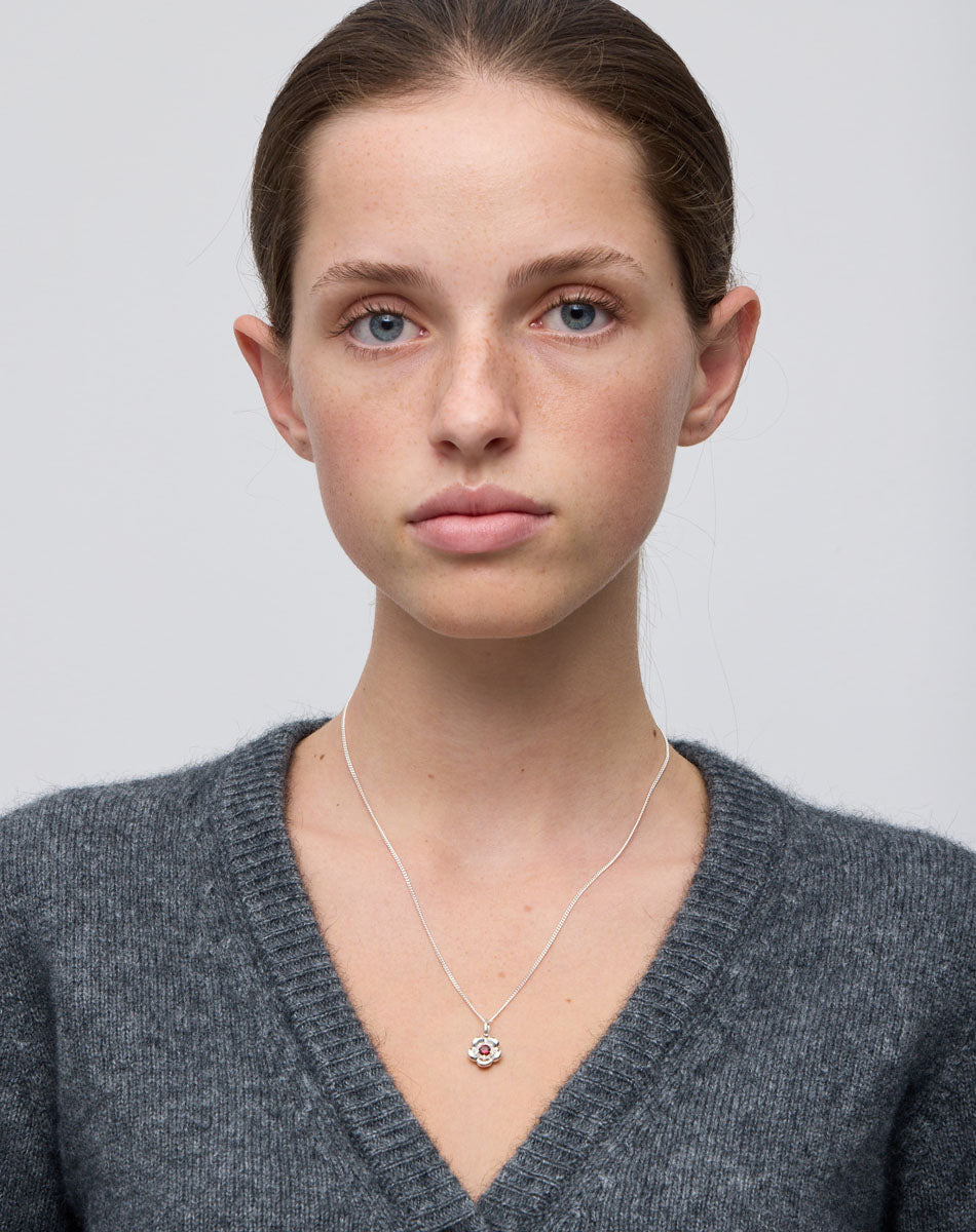 Meadowlark Jewellery’s floral Posie Charm Necklace in Sterling Silver, set with a single round brilliant cut African Garnet stone. Hung from a fine diamond curb chain. Inspired by classic floral motifs and our beloved Alba designs, a timeless symbol of grace, growth and renewal. Celebrating life’s continual renewal. From the Dreams collection.