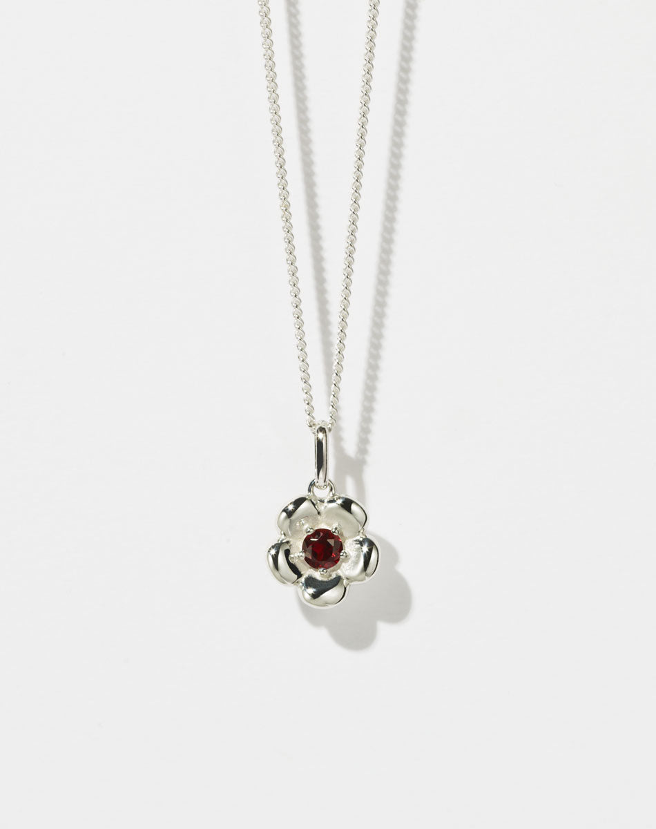 Meadowlark Jewellery’s floral Posie Charm Necklace in Sterling Silver, set with a single round brilliant cut African Garnet stone. Hung from a fine diamond curb chain. Inspired by classic floral motifs and our beloved Alba designs, a timeless symbol of grace, growth and renewal. Celebrating life’s continual renewal. From the Dreams collection.