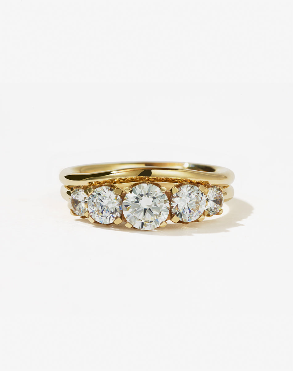A classic yellow gold, five stone diamond engagement ring. Set with  diamonds and shown with a matching wedding band.