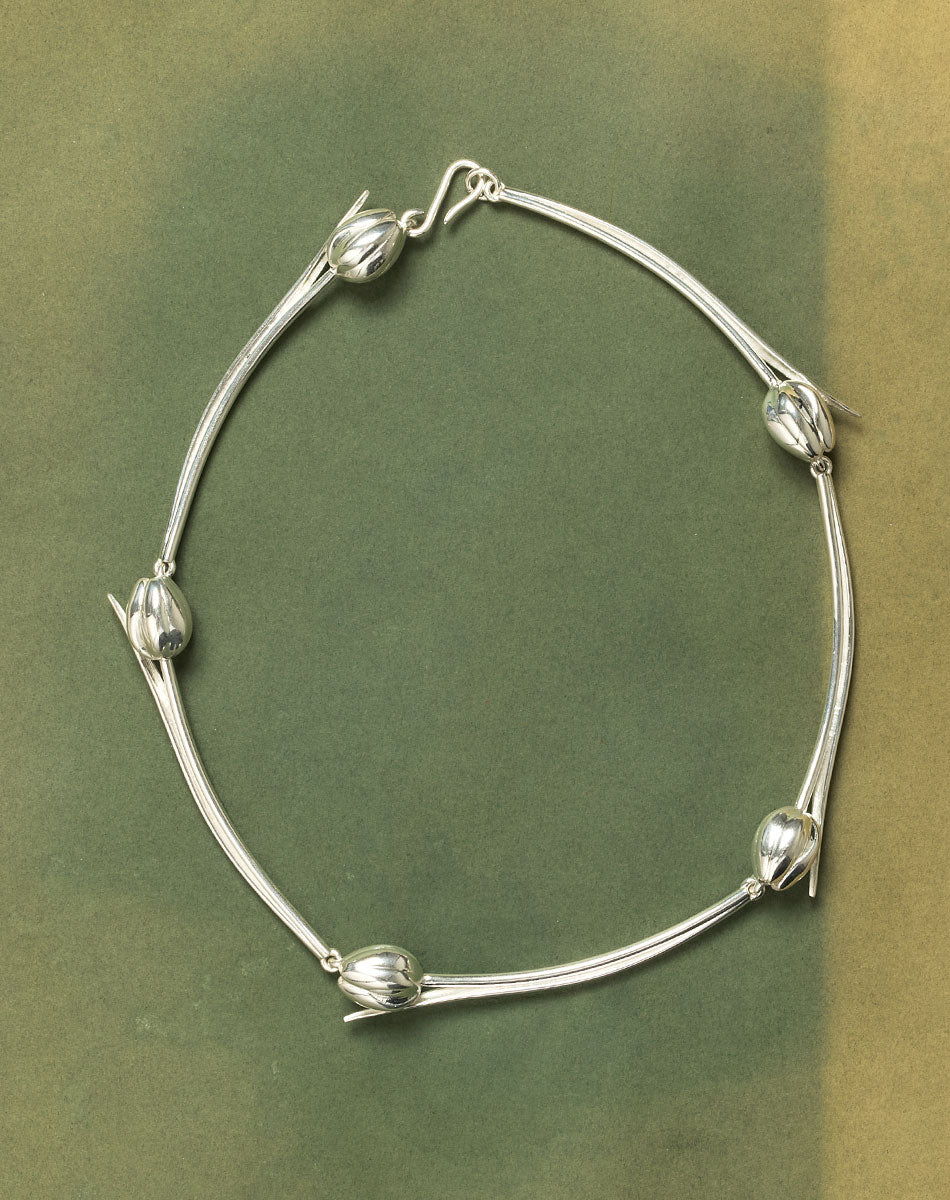 Silver necklace with tulip designs on a green background