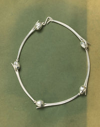 Silver necklace with tulip designs on a green background