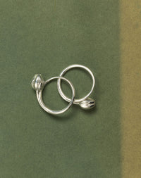 Pair of silver tulip rings on a green background