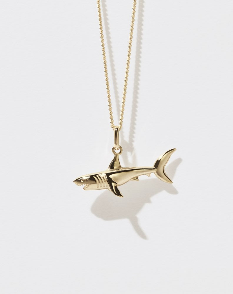 A gold shark charm necklace on a fine chain.