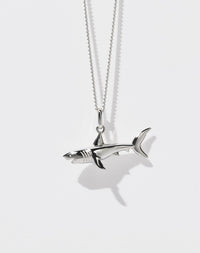 A sterling silver shark charm necklace with a fine chain.