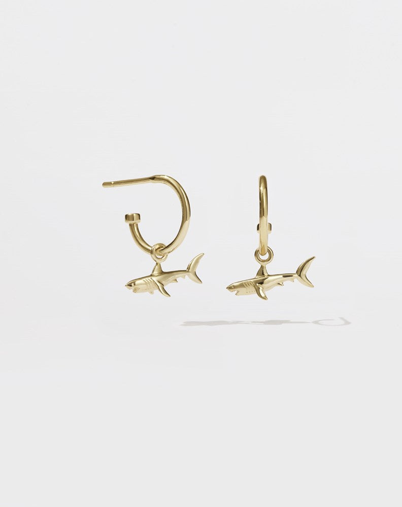 A pair of gold hoop earrings with shark charms attached