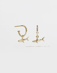 A pair of gold hoop earrings with shark charms attached