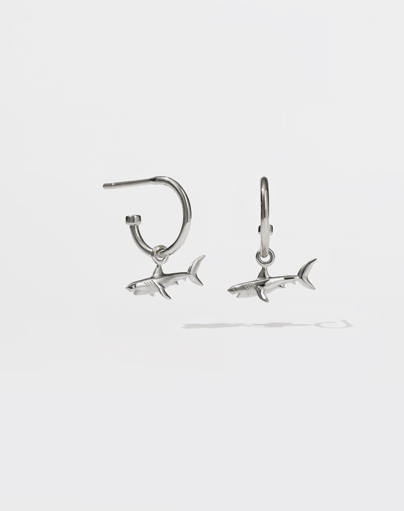 A pair of sterling silver hoop earrings with shark charms attached to them
