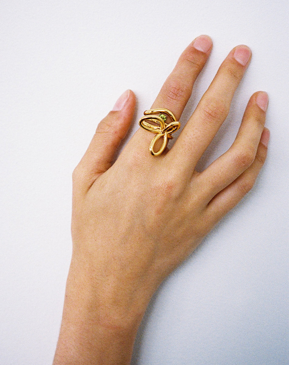Gold rings stacked on hand, flower ring, peridot stone and twisted band