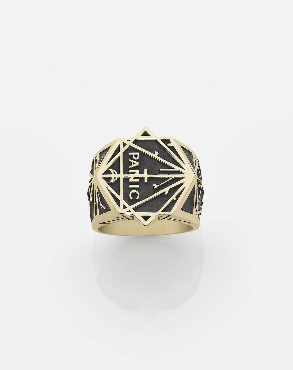 A heavy weighted gold ring with an oxidized finish and a geometric pattern design, featuring the text 'Panic' by Andrew Mcleod.