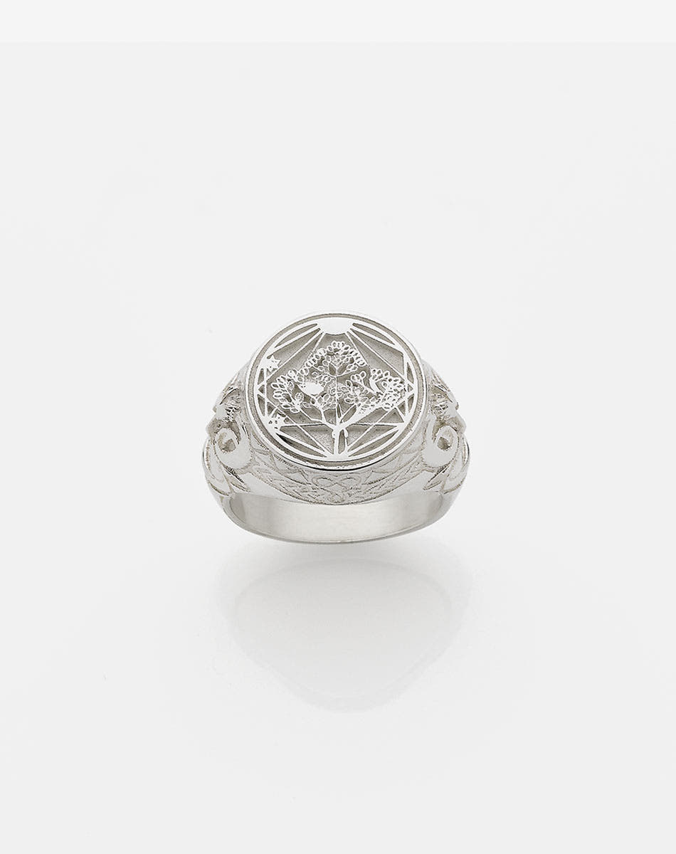 A sterling silver ring featuring a heavy weighted design with a central artwork, collaged together, with intricate detailing.